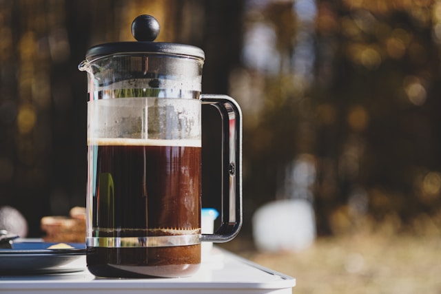 French Press vs Pour Over: Which Brewing Method Makes Better Coffee? Freshly brewed black coffee in a ceramic mug with coffee beans on a rustic wooden table